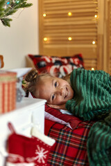 Little cute girl in bed under Christmas tree and dreaming of Santa