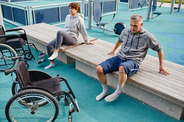 Two patients sitting on the bench outdoors they resting after sports exercises, they recovering...