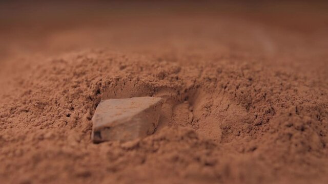 raw chocolate falling into cacoa powder slow motion