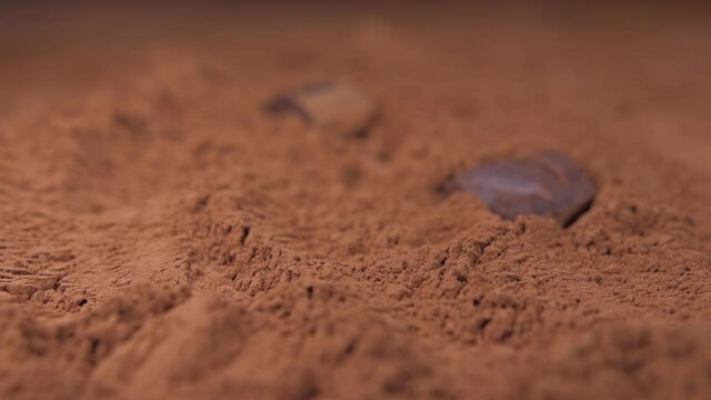 raw chocolate falling into cacoa powder slow motion