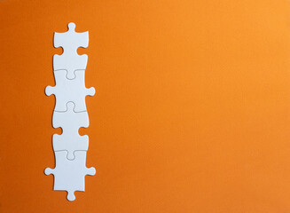 4 white jigsaw tiles joined together. horizontal image with orange background. copy space. space on the tiles to place letters or numbers.