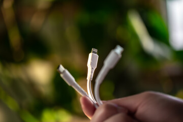 Three different connectors for charging a mobile phone on a blurred background.
