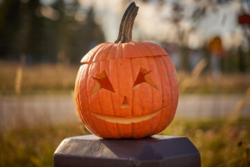 Halloween carved pumpkin with blurred road on the background.
