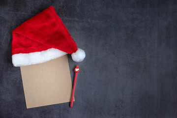A sheet of craft paper with a red Christmas cap and a pen with Santa. Letter to Santa Claus....