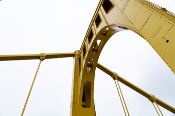 Upright support of a self anchored suspension bridge seen from below with cables against an overcast sky, horizontal aspect