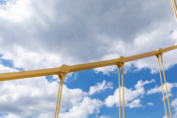 Bright yellow cables and joints of a self anchored suspension bridge against a blue sky with heavy...