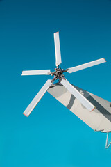 The tail rotor of the helicopter is silver against the blue sky on a clear sunny day, Military...
