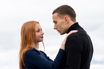 young couple stands hugging on the background of cloudy sky