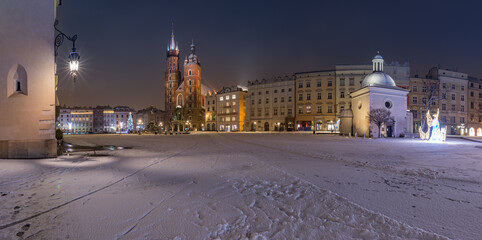 Krakow, Poland, snowy winter Main Square night panoramic view with St Mary's church