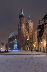 Naklejka na ściany i meble St Mary's church on snow covered Main Square in winter Krakow, illuminated in the night