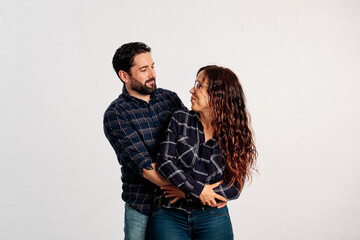 An adult couple in plaid shirts showing thumbs up to the camera and smiling against a white background - 463493006