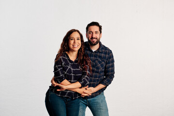An adult couple in plaid shirts showing thumbs up to the camera and smiling against a white background - 463493049
