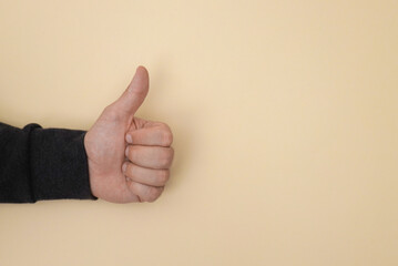 Closeup of male hand show thumbs up sign isolated on yellow background 