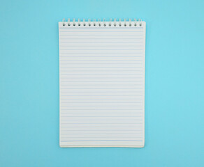 Close up of blank spiral notepad isolated on pastel blue background.