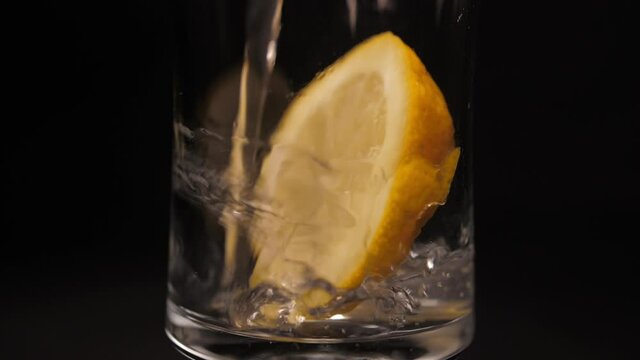 pouring soda water into glass with ice and lemon slow motion