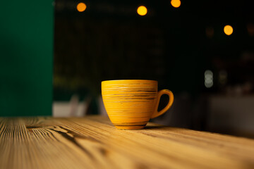 Bright orange cup on a blurred dark background with bokeh.
