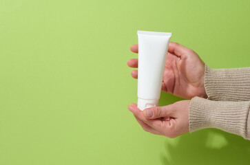 female hand holds empty white plastic tubes for cosmetics. Packaging for cream, gel, serum, advertising and product promotion