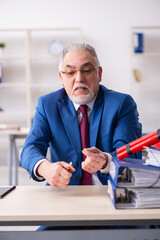 Fototapeta premium Old male employee with dynamite in the office
