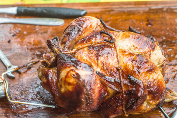 roasted chicken with chicken machine in the background, copy space and natural light, man holding a skewer with several chickens