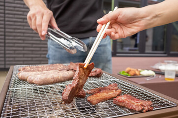 beef and pork sausages being grilled by a charcoal fire in the camp