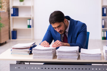 Young businessman employee and too much work in the office