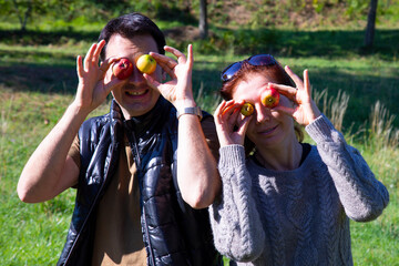 Funny couple on a walk in autumn ,  man and woman joke with small wild apples