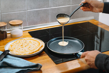 Person preparing pancakes in pan in the kitchen