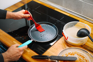 Person preparing pancakes in pan in the kitchen