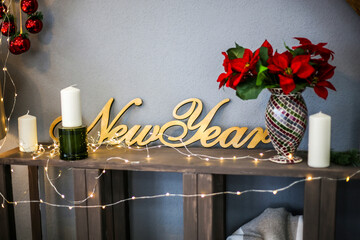 the inscription New Year in the interior with flowers and candles, along with a Christmas garland