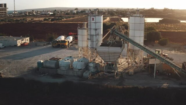 Huge industrial cement concrete silo production factory aerial. Storage reservoir towers in sunset light. Construction of manufacturing site. Manufacture road building industry. Cinematic panorama