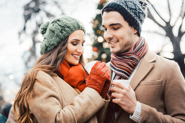 Couple with cups of mulled wine as drink on Christmas market