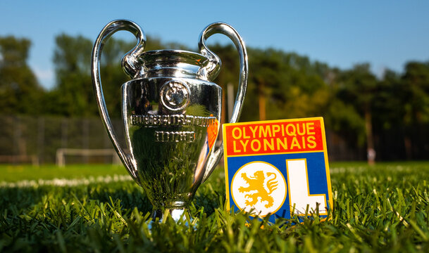 August 30, 2021, Lyon, France. The Emblem Of The Olympique Lyonnais Football Club And The UEFA Champions League Cup On A Green Lawn.