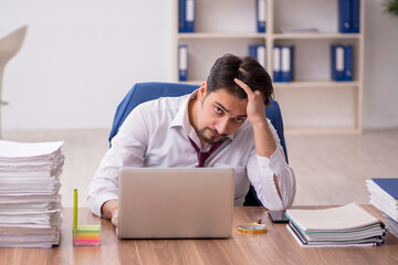 Young male employee and too much work in the office