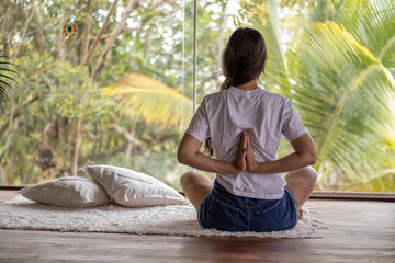 Woman practicing yoga - reverse prayer meditation looking at the Atlantic Forest of Brazil.