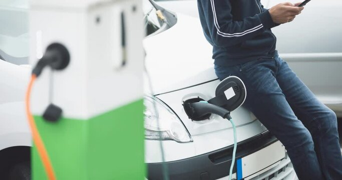 Mid section of caucasian man charging electric car