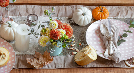 Festive table setting with pumpkins, candles and chrysanthemum flowers.