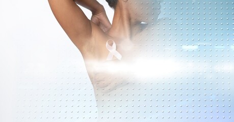Mid section of woman with a pink ribbon on her chest against rows of dots on blue background - Powered by Adobe