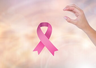 Pink ribbon icon and hand holding an invisible object against gradient blur background