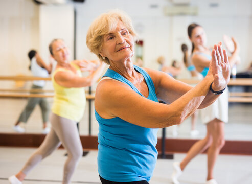 Old lady dancing with other women during group training in studio.