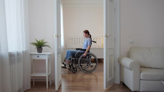 A young disabled woman is riding in her wheelchair around the room