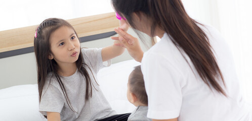 Obraz premium Young asian mother and daughter sitting playing with little baby girl on the bed together, mom and children relax, family of emotion and expression with happiness, parent and newborn, indoor.