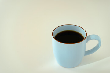 Hot black coffee in the blue coffee mug on the table.