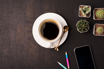 coffee cup with cell phone and cactus on the wooden background with copy space, top view