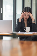 Stressed and tired young businesswoman with headache at workplace.