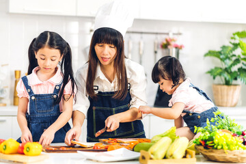 Naklejka premium Portrait of enjoy happy love asian family mother and little asian girl daughter child having fun help cooking food healthy eat together with fresh vegetable salad and sandwich ingredient in kitchen
