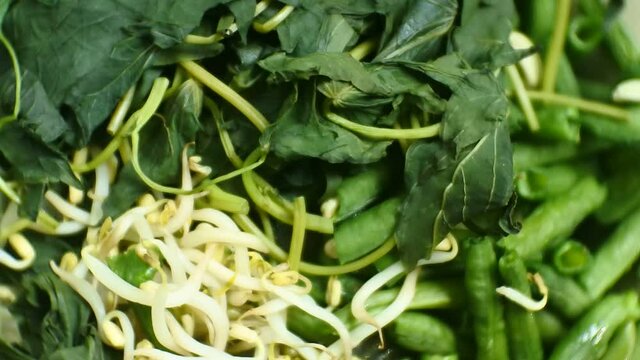 close up video HD of sweet potato leaves, long beans and boiled bean sprouts for making pecel rice, a typical food from East Java, Indonesia