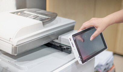 Businesswoman hand press button on panel of copy printer machine for process paperwork on laser...