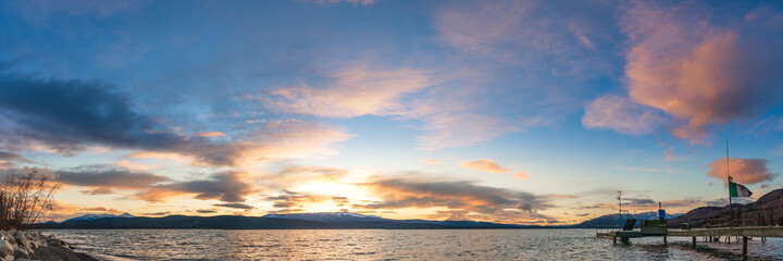 Yukon, Canada - 16th October 2021: Panoramic nature sunset in northern Canada taken during fall, autumn over a stunning lake with blue sky and dock. 
