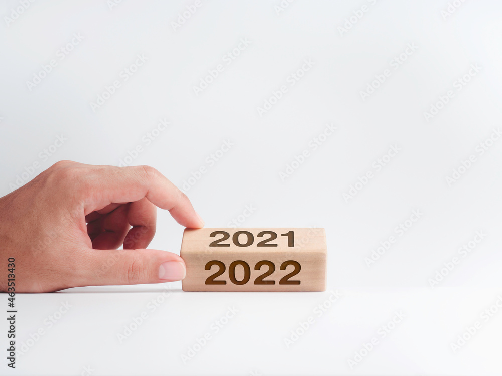 Poster hand holding the wooden cube block stick with calendar year numbers for the turning from 2021 to 202