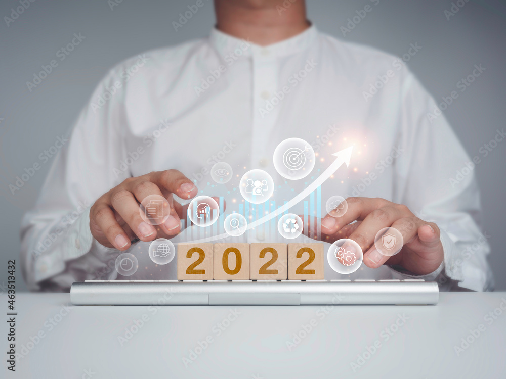 Poster the 2022 calendar year on wooden cube blocks on keyboard and businessman hands working with business